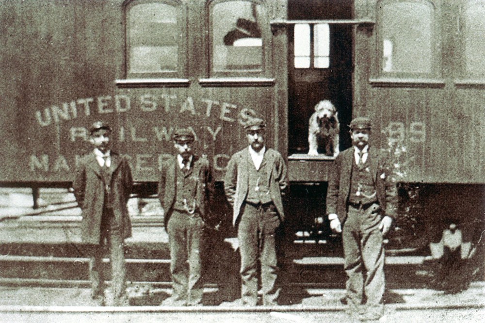 Owney on a train with 4 men standing for a portrait